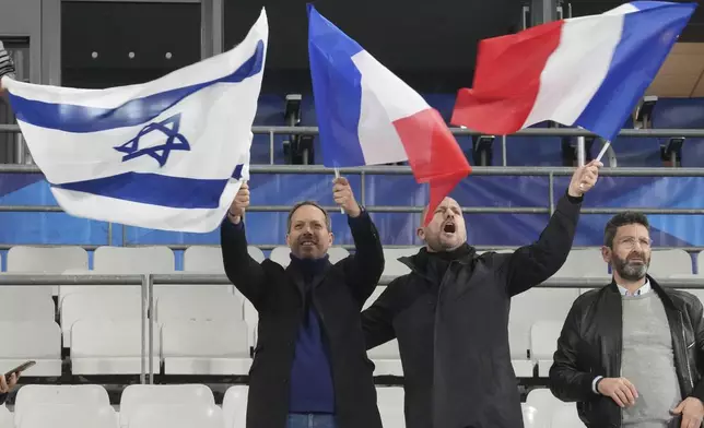 Men wave French and Israeli flags before the UEFA Nations League soccer match between France and Israel at the Stade de France stadium in Saint-Denis, outside Paris, Thursday Nov. 14, 2024. (AP Photo/Michel Euler)