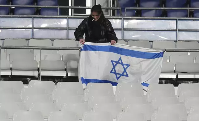 A woman adjusts an Israeli flag before the UEFA Nations League soccer match between France and Israel at the Stade de France stadium in Saint-Denis, outside Paris, Thursday Nov. 14, 2024. (AP Photo/Michel Euler)