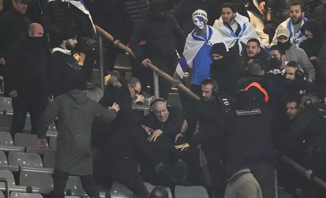 Security personnel detain a person as fans argue on stands during the UEFA Nations League soccer match between France and Israel at the Stade de France stadium in Saint-Denis, outside Paris, Thursday Nov. 14, 2024. (AP Photo/Thibault Camus)