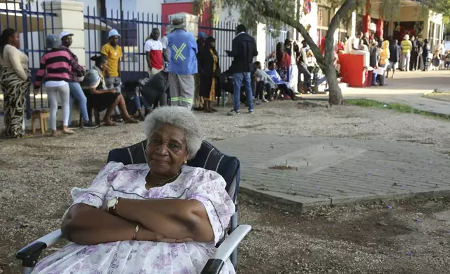 A woman sits as Namibians queue to cast their votes in a presidential election in Windhoek, Namibia Wednesday, Nov. 27, 2024. (AP Photo/Dirk Heinrich)