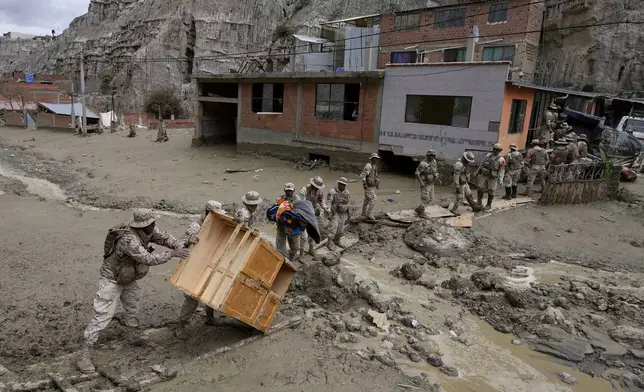 Soldiers recover a piece of furniture from a home flooded by a landslide caused by heavy rains in La Paz, Bolivia, Sunday, Nov. 24, 2024. (AP Photo/Juan Karita)