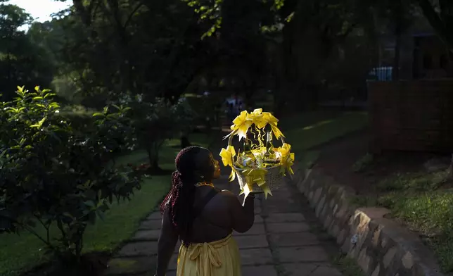 A woman carries a gift basket as she arrives at a park to attend a friend's birthday party, Sunday, Nov. 24, 2024, in Kampala, Uganda. (AP Photo/David Goldman)