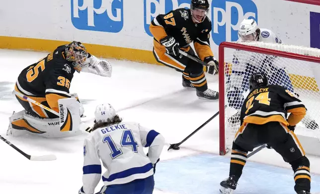 Tampa Bay Lightning's Brayden Point, top right behind goal, gets the game-winning overtime goal past Pittsburgh Penguins goaltender Tristan Jarry (35) and defenders Sidney Crosby (87) and Matt Grzelcyk (24) during an NHL hockey game Tuesday, Nov. 19, 2024, in Pittsburgh. The Lightning won 3-2. (AP Photo/Gene J. Puskar)