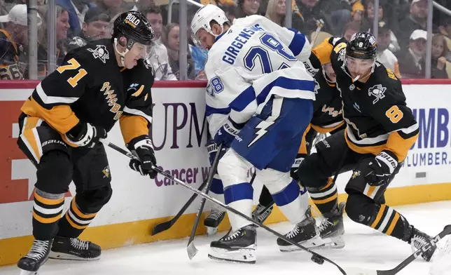 Pittsburgh Penguins' Evgeni Malkin (71) digs the puck out of a scrum in the corner with Tampa Bay Lightning's Zemgus Girgensons (28) defending during the second period of an NHL hockey game Tuesday, Nov. 19, 2024, in Pittsburgh. (AP Photo/Gene J. Puskar)