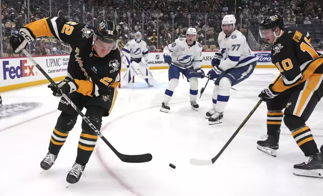 Pittsburgh Penguins' Sam Poulin (22) backhands a pass to Drew O'Connor (10) during the second period of an NHL hockey game against the Tampa Bay Lightning, Tuesday, Nov. 19, 2024, in Pittsburgh. (AP Photo/Gene J. Puskar)