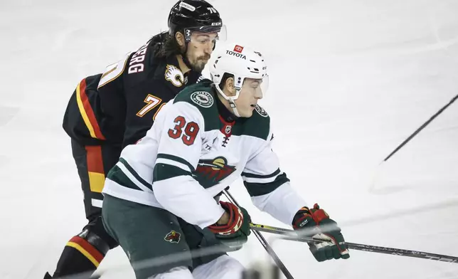 Minnesota Wild's Ben Jones (39) is checked by Calgary Flames' Ryan Lomberg (70) during first-period NHL hockey game action in Calgary, Alberta, Saturday, Nov. 23, 2024. (Jeff McIntosh/The Canadian Press via AP)