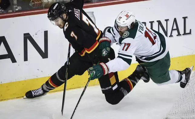 Minnesota Wild's Marcus Foligno, right, checks Calgary Flames' Kevin Bahl during second period NHL hockey action in Calgary on Saturday, Nov. 23, 2024. (Jeff McIntosh/The Canadian Press via AP)