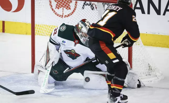 Minnesota Wild goalie Filip Gustavsson, left, blocks the net on Calgary Flames' Kevin Rooney during second period NHL hockey action in Calgary on Saturday, Nov. 23, 2024. (Jeff McIntosh/The Canadian Press via AP)