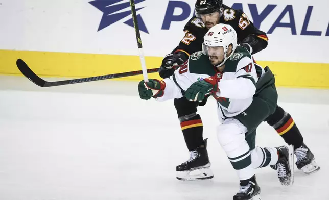 Minnesota Wild's Marcus Johansson, right, is checked by Calgary Flames' MacKenzie Weegar, left, during second-period NHL hockey game action in Calgary, Alberta, Saturday, Nov. 23, 2024. (Jeff McIntosh/The Canadian Press via AP)