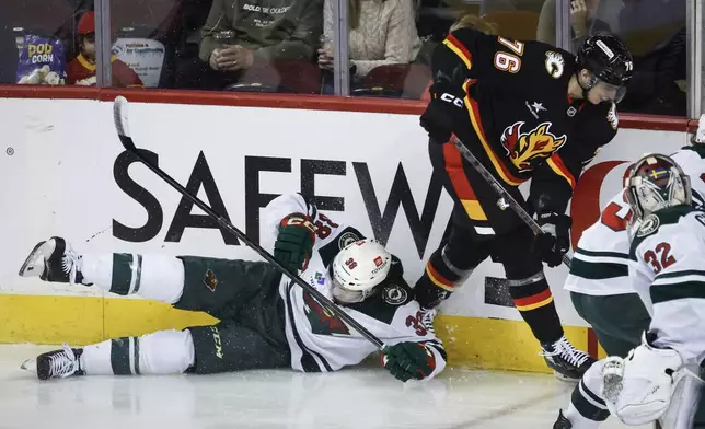 Minnesota Wild's Ryan Hartman, left, misses a check against Calgary Flames' Martin Pospisil (76) during second-period NHL hockey game action in Calgary, Alberta, Saturday, Nov. 23, 2024. (Jeff McIntosh/The Canadian Press via AP)