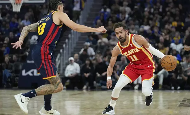 Atlanta Hawks guard Trae Young, right, moves the ball while defended by Golden State Warriors forward Lindy Waters III during the first half of an NBA basketball game Wednesday, Nov. 20, 2024, in San Francisco. (AP Photo/Godofredo A. Vásquez)