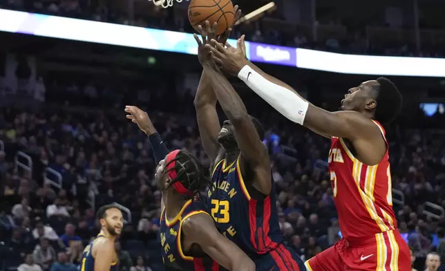 Golden State Warriors forward Draymond Green (23) and Atlanta Hawks forward Onyeka Okongwu, right, compete for possession of the ball during the first half of an NBA basketball game Wednesday, Nov. 20, 2024, in San Francisco. (AP Photo/Godofredo A. Vásquez)