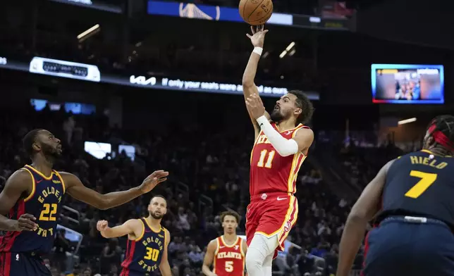 Atlanta Hawks guard Trae Young (11) shoots in front of Golden State Warriors forward Andrew Wiggins (22) during the first half of an NBA basketball game Wednesday, Nov. 20, 2024, in San Francisco. (AP Photo/Godofredo A. Vásquez)