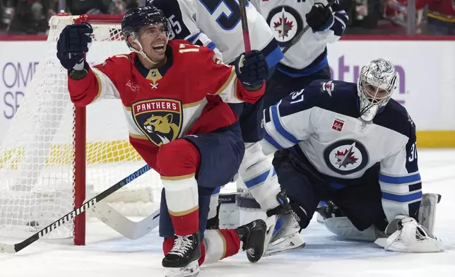 Florida Panthers center Evan Rodrigues, left, reacts after scoring against Winnipeg Jets goaltender Connor Hellebuyck, right, during the second period of an NHL hockey game, Saturday, Nov. 16, 2024, in Sunrise, Fla. (AP Photo/Lynne Sladky)