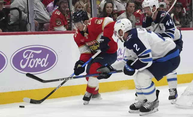 Florida Panthers right wing Mackie Samoskevich (25) and Winnipeg Jets defenseman Dylan DeMelo (2) go for the puck during the second period of an NHL hockey game, Saturday, Nov. 16, 2024, in Sunrise, Fla. (AP Photo/Lynne Sladky)