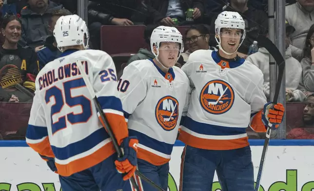 New York Islanders' Pierre Engvall, right, celebrates with teammates Dennis Cholowski, left, and Simon Holmstrom, center, after scoring against the Vancouver Canucks during second-period NHL hockey game action in Vancouver, British Columbia, Thursday, Nov. 14, 2024.(Rich Lam/The Canadian Press via AP)