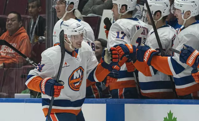 New York Islanders' Scott Mayfield celebrates with teammates after scoring against the Vancouver Canucks during second-period NHL hockey game action in Vancouver, British Columbia, Thursday, Nov. 14, 2024.(Rich Lam/The Canadian Press via AP)