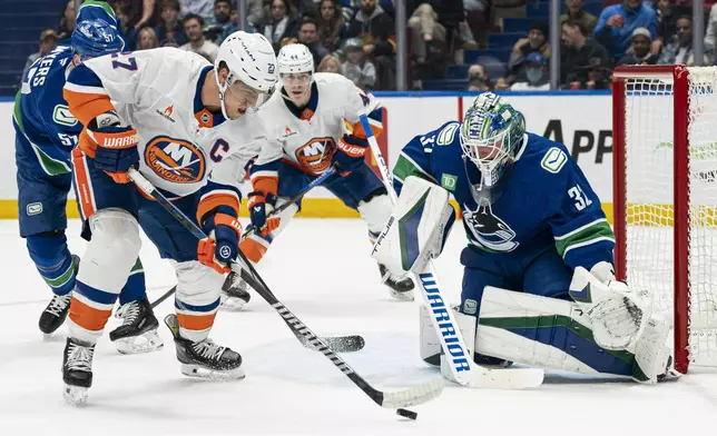 New York Islanders' Anders Lee, left, settles the puck in front of Vancouver Canucks goalie Kevin Lankinen, right, during the first period of an NHL hockey game, Thursday, Nov. 14, 2024 in Vancouver, British Columbia. (Rich Lam/The Canadian Press via AP)