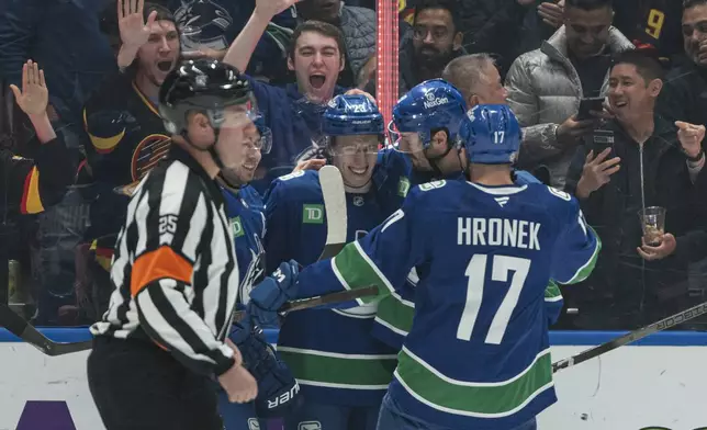 Vancouver Canucks' Jonathan Lekkerimaki (23) celebrates with teammates J.T. Miller, second right, and Filip Hronek after scoring a goal against the New York Islanders during the first period of an NHL hockey game, Thursday, Nov. 14, 2024 in Vancouver, British Columbia. (Rich Lam/The Canadian Press via AP)