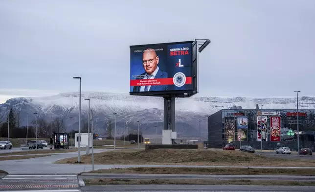 A Bilboard of the Democratic Party (Lýðræðisflokkurinn) reading "Let's limit the interest rate by law to a maximum of 4%" is backdropped by Mt. Esja covered with fresh snow, in Reykjavik, Iceland, Friday, Nov. 29, 2024. (AP Photo Marco Di Marco)