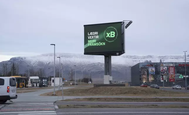 A bilboard of the Progressive Party (Framsóknarflokkurinn) reading "Lower interest rates - More Progress", is backdropped by Mt. Esja covered with fresh snow in Reykjavik, Iceland, Friday, Nov. 29, 2024. (AP Photo Marco Di Marco)