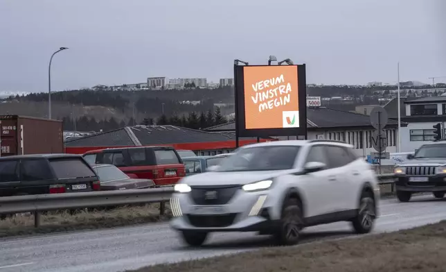 Cars drive past a bilboard of the Left Green Party (Vinstri græn) reading "Let's stay on the left side, in Reykjavik, Iceland, Friday, Nov. 29, 2024. (AP Photo Marco Di Marco)