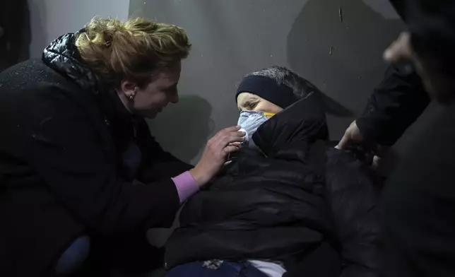 An elderly woman is being cared after clashes between riot police and opposition supporters in Tirana, Albania, Tuesday, Nov. 26, 2024 during an anti-government protest over the arrests of their leader Sali Berisha and former President Ilir Meta in separate corruption cases, saying the charges are politically motivated. (AP Photo/Vlasov Sulaj)