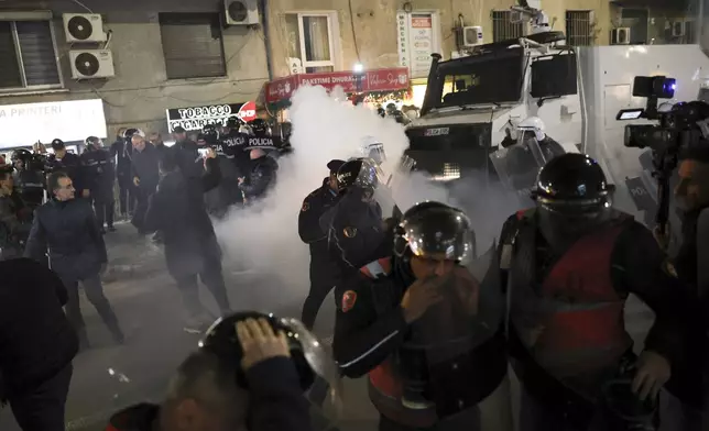 Opposition Supporters and riot police run out of a gas canister thrown by Albania's police during a protest, in Tirana , Albania , Tuesday, Nov. 26, 2024 over the arrests of their leader Sali Berisha and former President Ilir Meta in separate corruption cases, saying the charges are politically motivated. (AP Photo/Vlasov Sulaj)