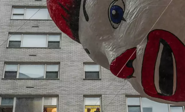 People watch handlers guide the Ronald McDonald balloon down Sixth Avenue during the Macy's Thanksgiving Day Parade, Thursday, Nov. 28, 2024, in New York. (AP Photo/Julia Demaree Nikhinson)