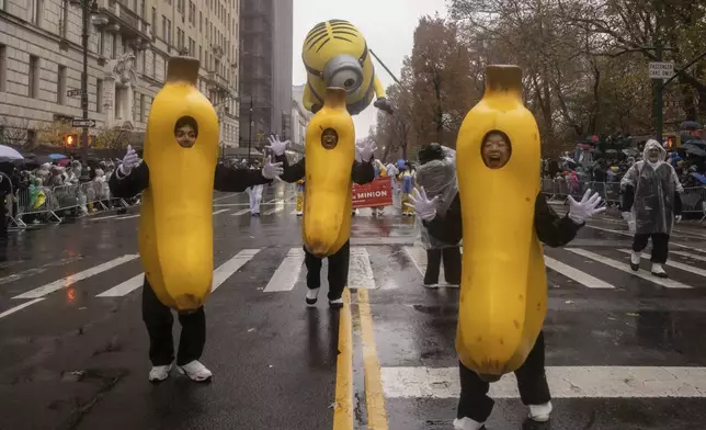 Parade performers lead the Stuart the Minion float down Central Park West during the Macy's Thanksgiving Day parade, Thursday, Nov. 28 2024, in New York. (AP Photo/Yuki Iwamura)