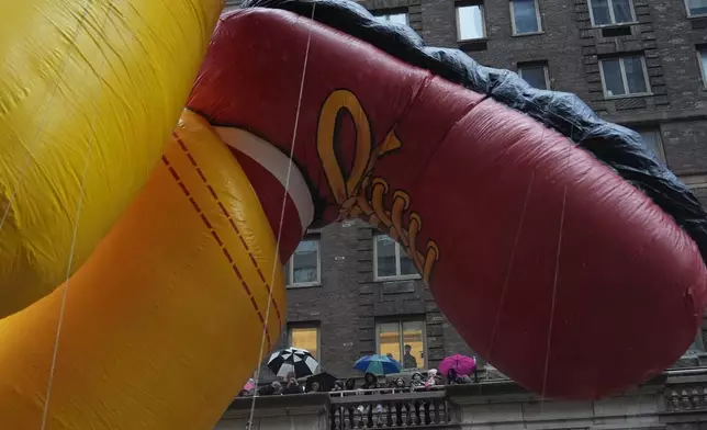 Spectators watch from an apartment building terrace as handlers pull the Ronald McDonald balloon down Sixth Avenue during the Macy's Thanksgiving Day Parade, Thursday, Nov. 28, 2024, in New York. (AP Photo/Julia Demaree Nikhinson)