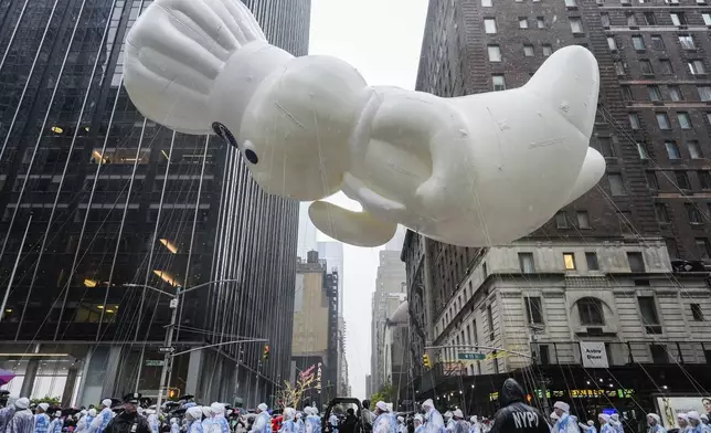 Handlers guide the Pillsbury Doughboy balloon down Sixth Avenue during the Macy's Thanksgiving Day Parade, Thursday, Nov. 28, 2024, in New York. (AP Photo/Julia Demaree Nikhinson)