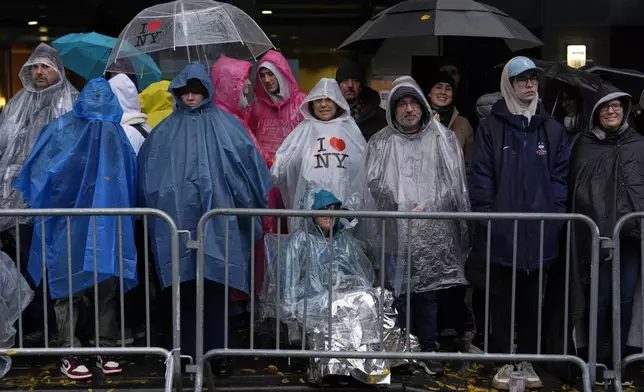 People stand in the rain along Sixth Avenue ahead of the start of the Macy's Thanksgiving Day Parade, Thursday, Nov. 28, 2024, in New York. (AP Photo/Julia Demaree Nikhinson)