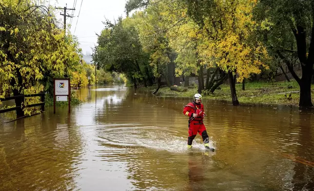 Firefighter Eugene Stipanov walks through floodwaters while responding to a rescue call in unincorporated Sonoma County, Calif., on Friday, Nov. 22, 2024. (AP Photo/Noah Berger)