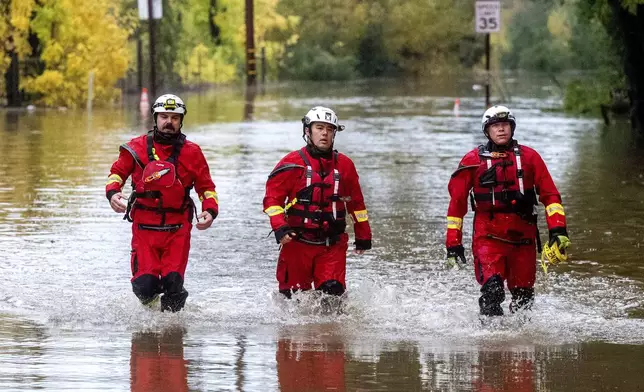 Firefighters walk through floodwaters while responding to a rescue call in unincorporated Sonoma County, Calif., on Friday, Nov. 22, 2024. (AP Photo/Noah Berger)