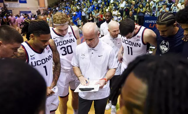 UConn head coach Dan Hurley huddles with his team, including guard Solo Ball (1), forward Liam McNeeley (30) and forward Alex Karaban (11) before facing Memphis in an NCAA college basketball game at the Maui Invitational Monday, Nov. 25, 2024, in Lahaina, Hawaii. (AP Photo/Lindsey Wasson)