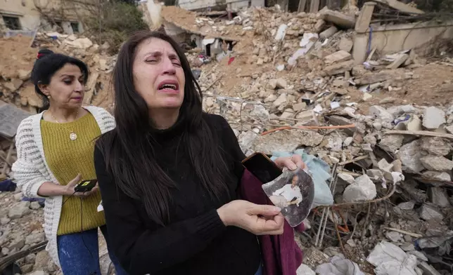 Zeina Rida Jawhari, reacts after recovering a photo of her father from the rubble of her destroyed house in Baalbek, eastern Lebanon, Thursday, Nov. 28, 2024. (AP Photo/Hassan Ammar)