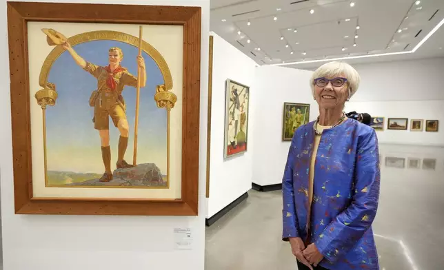 Judge Barbara Houser poses for a photo at Heritage Auctions in Dallas, Thursday, Oct. 17, 2024, by a collection of paintings from the Boy Scouts of America's storied collection that will be going up for auction. (AP Photo/Tony Gutierrez)