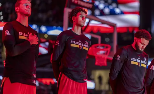 Atlanta Hawks forward Zaccharie Risacher, center, stands for the national anthem before an Emirates NBA Cup basketball game against the Cleveland Cavaliers, Friday, Nov. 29, 2024, in Atlanta. (AP Photo/Erik Rank)