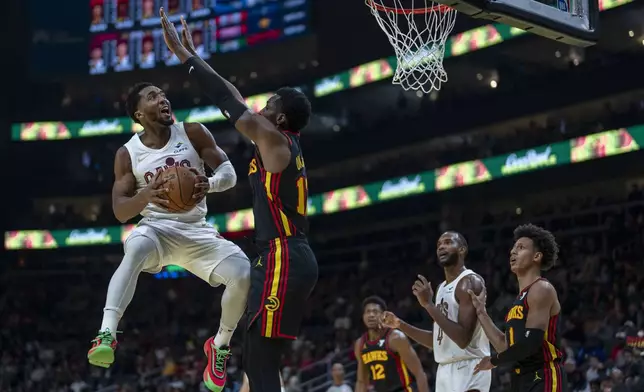 Cleveland Cavaliers guard Donovan Mitchell, left, attempts a slam-dunk against the Atlanta Hawks during the first half of an Emirates NBA Cup basketball game Friday, Nov. 29, 2024, in Atlanta. (AP Photo/Erik Rank)