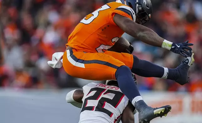 Denver Broncos running back Audric Estime (23) leaps over Atlanta Falcons cornerback Clark Phillips III (22) during the second half of an NFL football game, Sunday, Nov. 17, 2024, in Denver. (AP Photo/David Zalubowski)