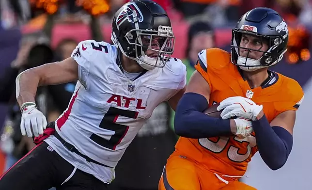 Atlanta Falcons wide receiver Drake London (5) hits Denver Broncos linebacker Cody Barton (55) after Barton's interception during the second half of an NFL football game, Sunday, Nov. 17, 2024, in Denver. (AP Photo/David Zalubowski)