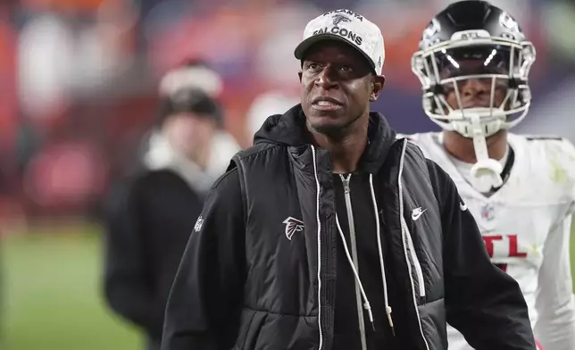 Atlanta Falcons head coach Raheem Morris, front, looks at the scoreboard as he leaves the field with wide receiver Darnell Mooney in tow after an NFL football game against the Denver Broncos, Sunday, Nov. 17, 2024, in Denver. (AP Photo/David Zalubowski)