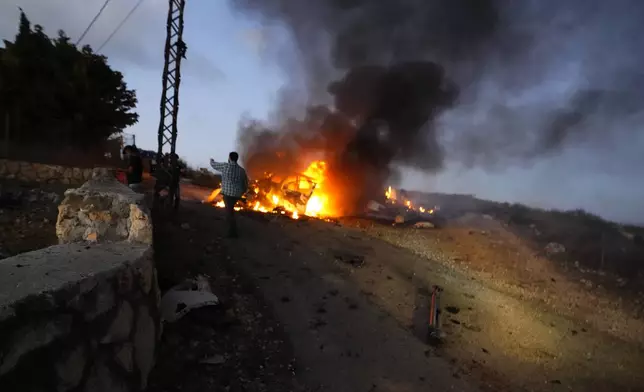 A journalist's car burns after an Israeli shell landed in a gathering of international journalists covering clashes in the Alma al-Shaab border village with Israel, south Lebanon, Friday, Oct. 13, 2023. (AP Photo/Hassan Ammar)