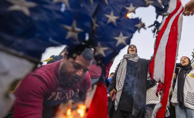 A protester burns an American flag as others shout slogans against Israel and the United States during a protest in solidarity with the Palestinian people in Gaza in Beirut, Lebanon, Saturday, March 2, 2024. (AP Photo/Hassan Ammar)