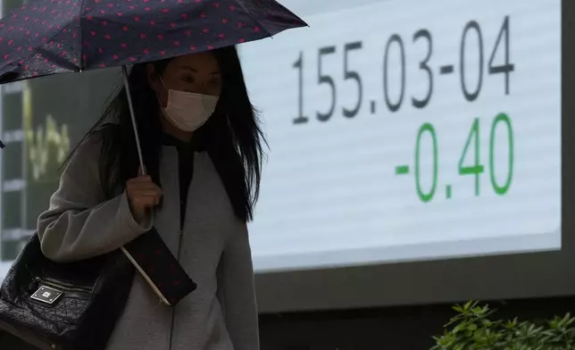 A woman walks by a monitor showing Japan's foreign exchange rate against the U.S. dollar at a securities firm in Tokyo, Thursday, Nov. 21, 2024. (AP Photo/Hiro Komae)