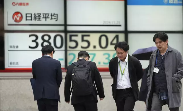 People walk by monitors showing Japan's Nikkei 225 index at a securities firm in Tokyo, Thursday, Nov. 21, 2024. (AP Photo/Hiro Komae)