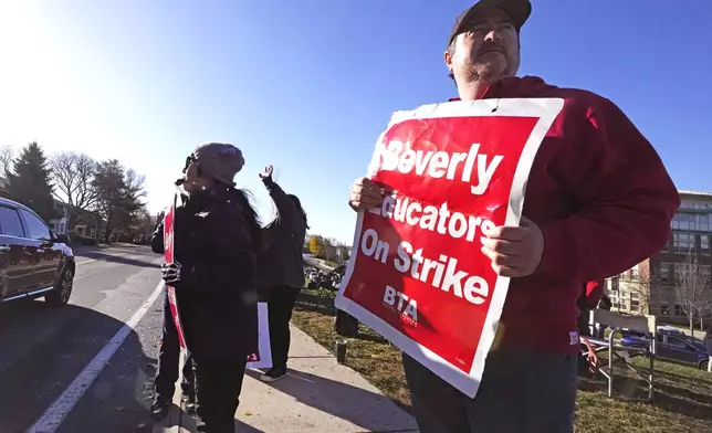 Striking teachers and supporters stand on the picket line, Friday, Nov. 22, 2024, in Beverly, Mass., to call attention to pay, paid parental leave, and other contract issues. (AP Photo/Charles Krupa)