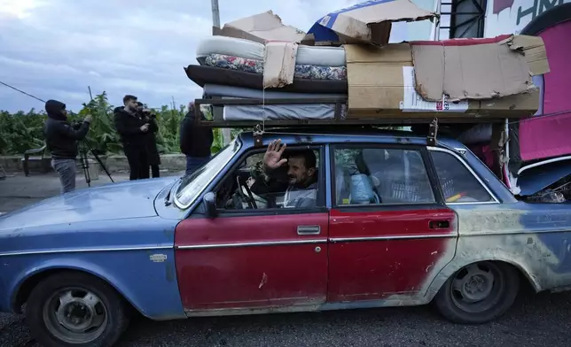 A man who is returning to his village waves as he carries his belongings on his car after the ceasefire between Hezbollah and Israel began early morning, in Tyre, south Lebanon, Wednesday, Nov. 27, 2024. (AP Photo/Hussein Malla)