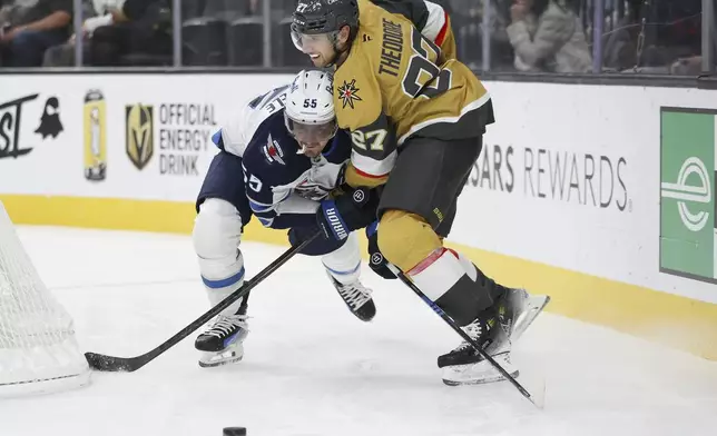 Winnipeg Jets center Mark Scheifele (55) and Vegas Golden Knights defenseman Shea Theodore (27) collide during the first period of an NHL hockey game Friday, Nov. 29, 2024, in Las Vegas. (AP Photo/Ian Maule)